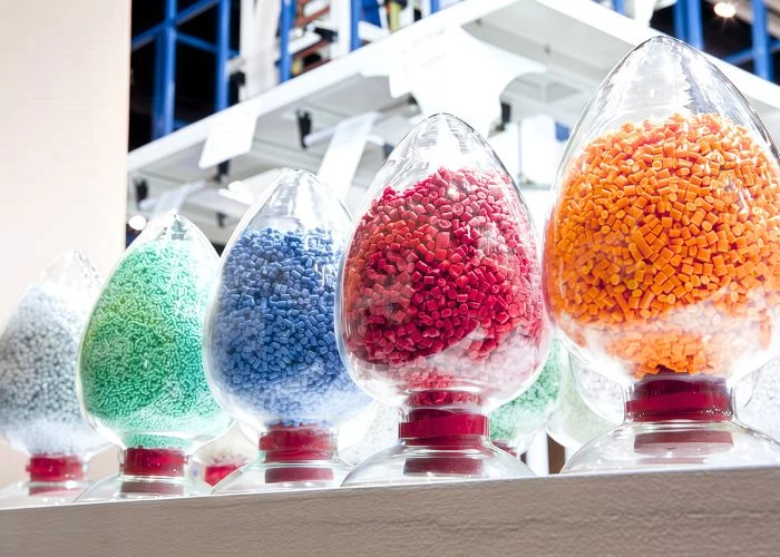 Green, blue, red and orange plastic pellets placed inside the container, industrial raw material sample photography for plastic formulation display