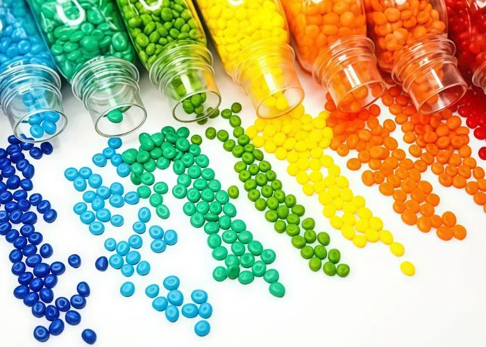 Display of various different colored raw plastic resin pellets, polymer material samples